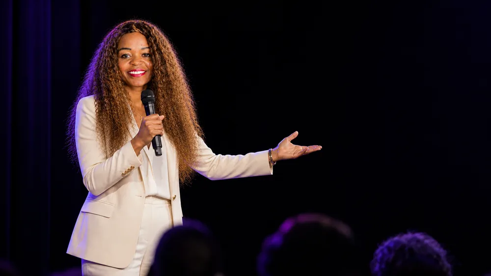 Paulette Fotsing sur scène, micro à la main, devant une salle